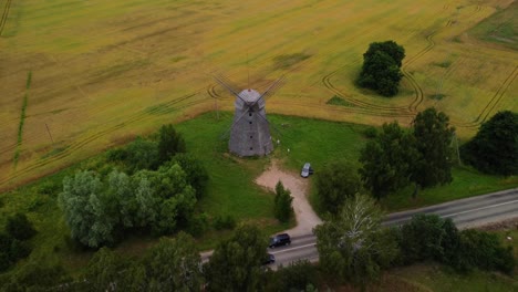 toma aérea de un antiguo molino de viento en el campo junto a la carretera, alejándose