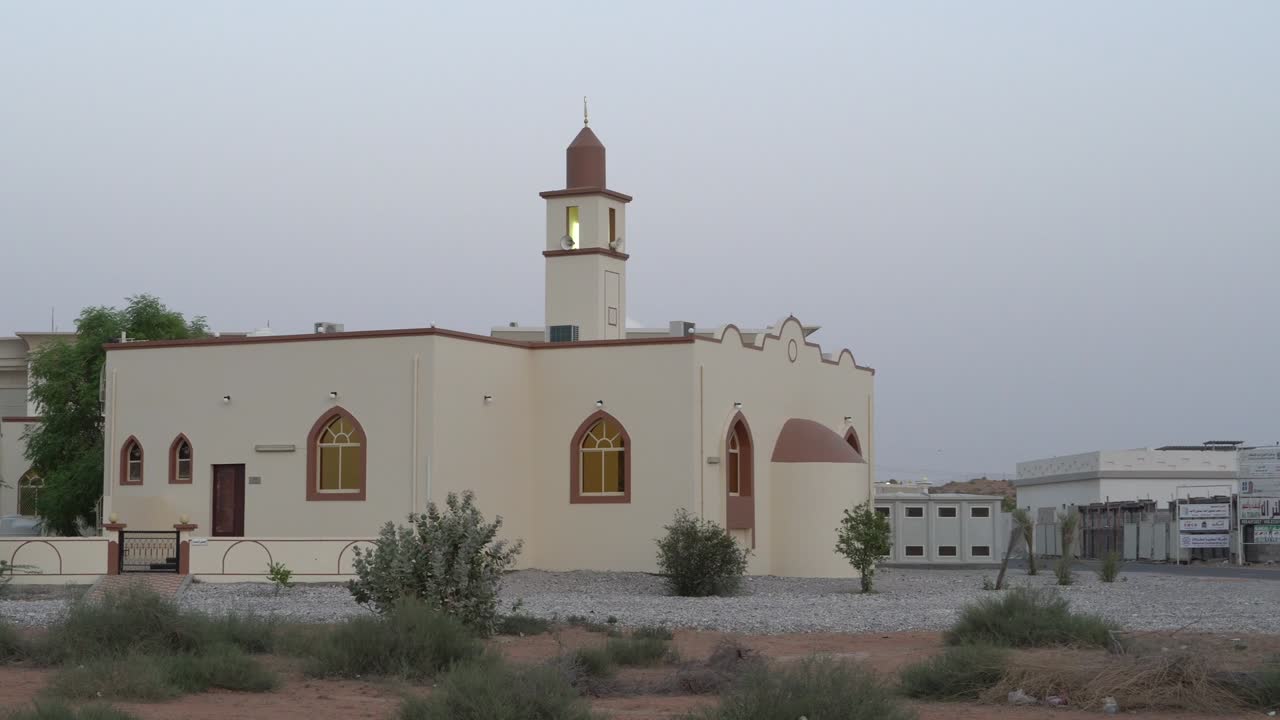 mezquita blanca en una zona residencial en el medio oriente con un cielo azul en el sol de la tarde. llamada a la oración durante el ramadán.