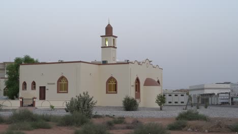 mezquita blanca en una zona residencial en el medio oriente con un cielo azul en el sol de la tarde. llamada a la oración durante el ramadán.