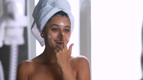 woman applying face cream in the bathroom