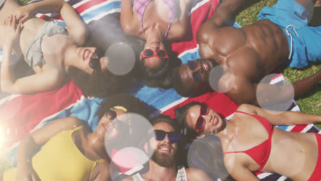 animation of spots of light over diverse friends wearing sunglasses lying on glass on holiday