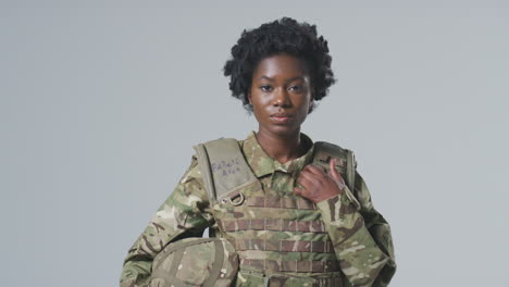 Studio-Portrait-Of-Serious-Young-Female-Soldier-In-Military-Uniform-Against-Plain-Background