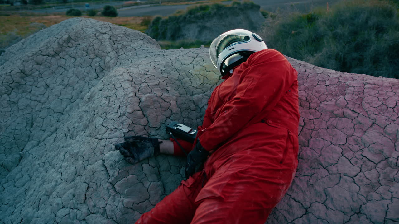 astronauta en traje naranja y casco se derrumbó en la roca aterrizó en un nuevo planeta