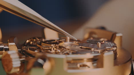 watchmaker assembling and putting back in place the piece and mechanism of mechanical watch by tweezers