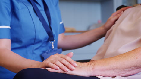 close up of nurse comforting senior woman on home visit