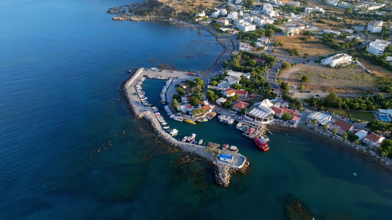 High angle drone shot orbiting the Faliraki harbor, golden hour in Rhodes, Greece