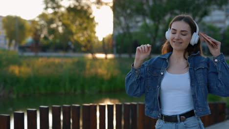 young woman enjoying music in a park at sunset