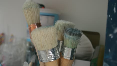 artists brushes in glass jar, in a busy home studio