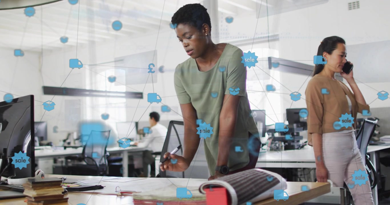 Blue icons appearing and growing, woman leaning over desk marking plans aligning design in office