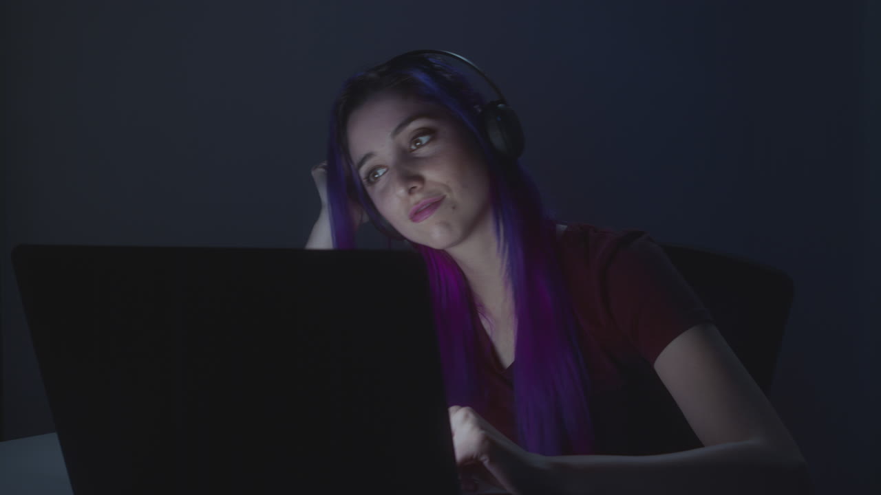 una joven divirtiéndose en su computadora portátil mientras escucha música.