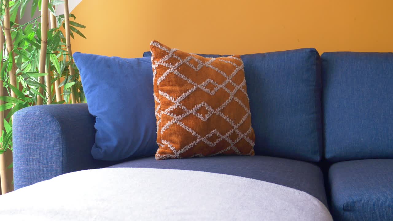 acogedora sala de estar con sofá azul y almohadas de lanzamiento naranja