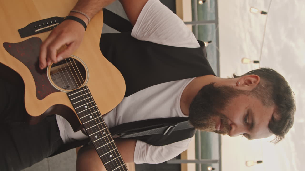 Vertical Shot of Man Playing Guitar on Rooftop Terrace