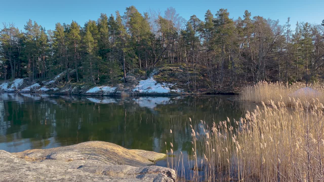 Hiljainen talvipäivä Tukholman saaristossa, lumilaikkuja ja tyyni vesi.