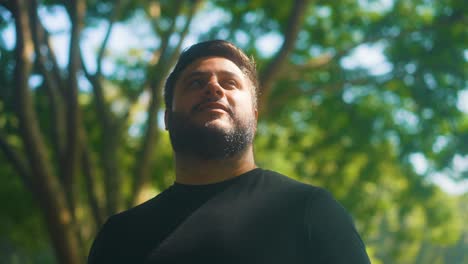 close up young happy bearded man standing in nature breathes fresh air