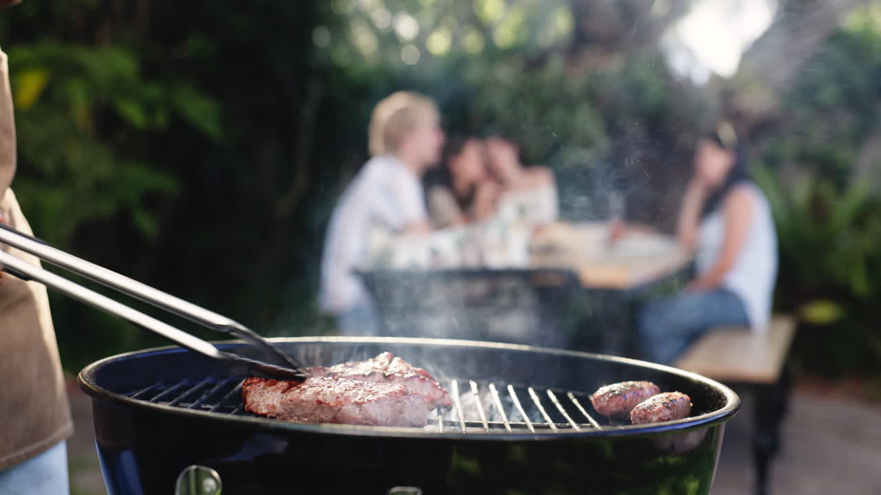 Persona che griglia bistecche e salsicce su un barbecue in giardino