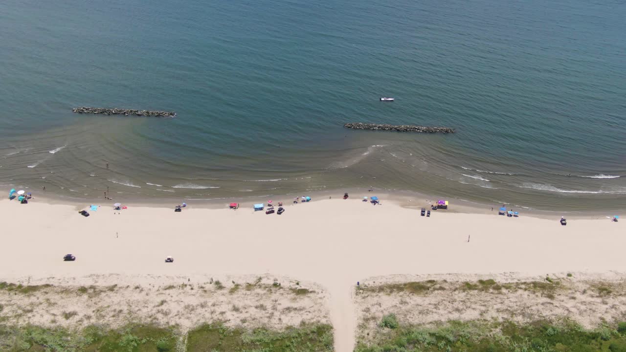Wide drone shot capturing Grand Isle’s coastline, ocean waves, tents, and beachgoers—showcasing Louisiana’s coastal charm, tourism growth, and community recreation