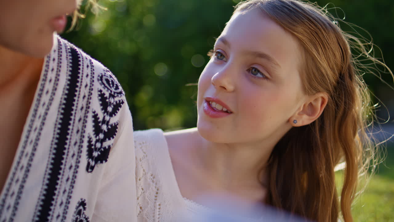 Mom kid reading book sitting nature closeup. Smiling mother daughter resting