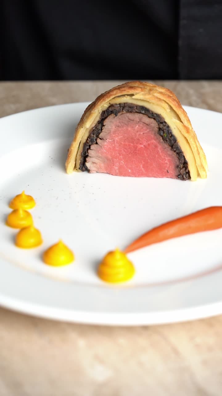 A chief prepares beef wellington sliced plate, close up shot, insert shot