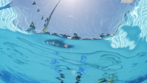 underwater view looking up at people waiting to enter the water for a scuba diving course