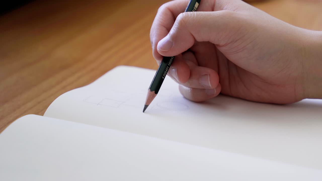 dibujar con lápiz en un cuaderno de bocetos negro en un escritorio de madera