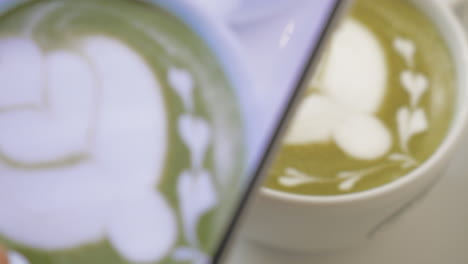 en la mesa hay una taza de café con espuma y patrón y la chica toma una foto de la taza en el teléfono móvil