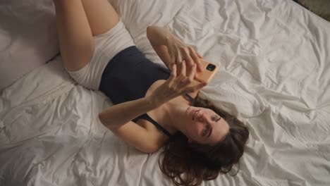 una mujer tomando una selfie en una cama.