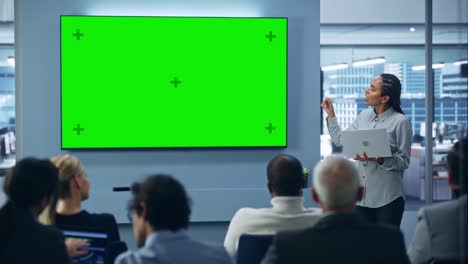 modern product presentation event: black businesswoman speaks, uses green chroma key screen wall tv. press conference for group of diverse investors, digital entrepreneurs, businesspeople