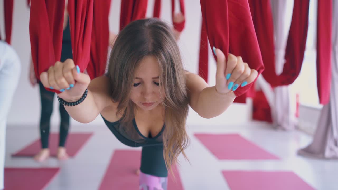 красивая молодая женщина практикует антигравитационную йогу воинскую асану