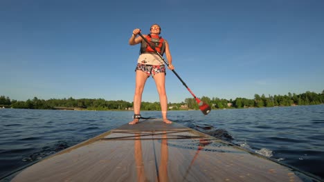 woman standup paddle boarding angle from tip of board in sunset lighting