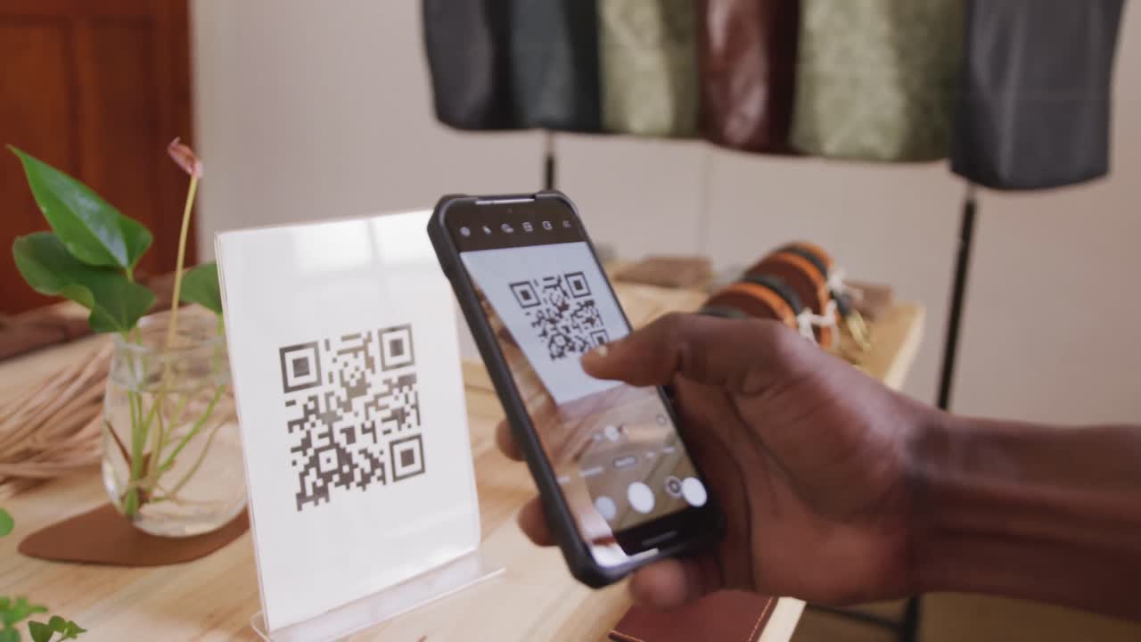 Hand of african american craftsman scanning qr code in leather workshop
