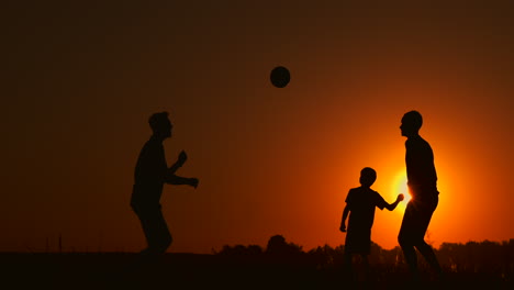 three boys playing soccer at sunset. silhouette of children playing with a ball at sunset. the concept of a happy family.