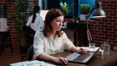 smiling staff member planning marketing project on laptop late at night,