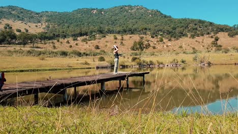 Girl-bass-fishing-from-a-pier-at-beautiful-lake-on-a-sunny-day