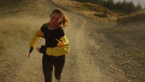 Tired-athlete-jogging-on-dirty-road.-Girl-in-sportswear-running-in-mountains