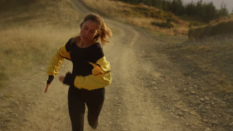 tired athlete jogging on dirty road. girl in sportswear running in mountains