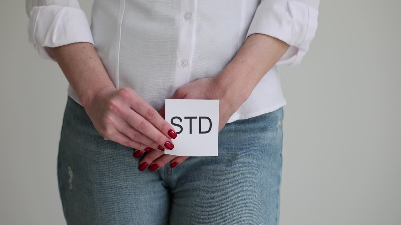 Person holding STD card covering groin area