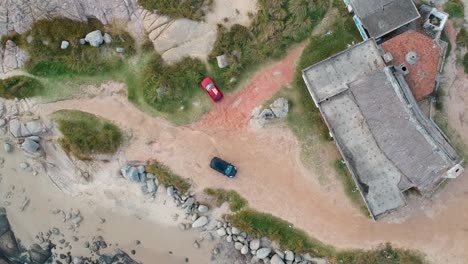 Drone-over-the-red-car-parked-on-the-ocean-shore-of-the-ocean-in-Rocha,-Uruguay