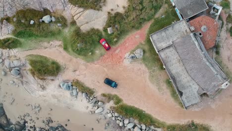 drone over the red car parked on the ocean shore of the ocean in rocha, uruguay