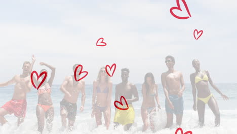 animation of red hearts over happy diverse group of friends on beach