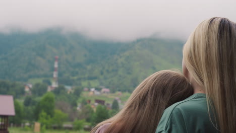 Mother-and-little-daughter-look-at-misty-distant-mountains