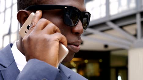 serious black business man talking by phone in the street
