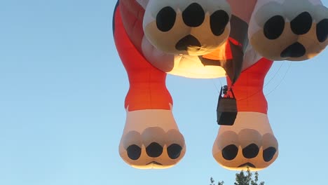 a dog shaped hot air balloon with a live flame that keeps the balloon flying over a beautiful city