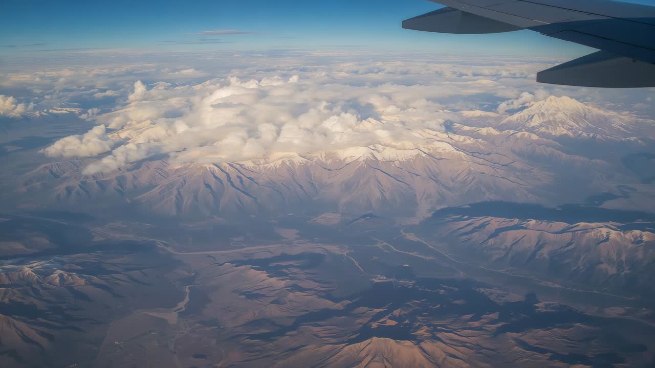 Gliding passenger plane camera capturing mountains as plane moves, revealing valleys and wing