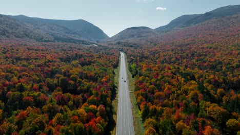 Vistas-De-La-Carretera-Centradas-Mientras-Los-Autos-Pasan-Rodeados-De-Follaje-De-Otoño-En-New-Hampshire-Desde-Una-Vista-Aérea