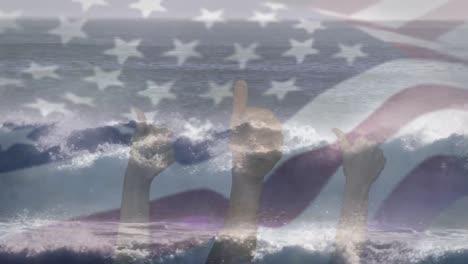 digital composition of waving us flag over hands showing thumbs up against waves in the sea