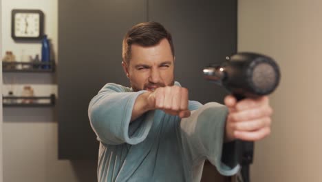 retrato de un hombre satisfecho con un secador de pelo en las manos imaginándose como superman
