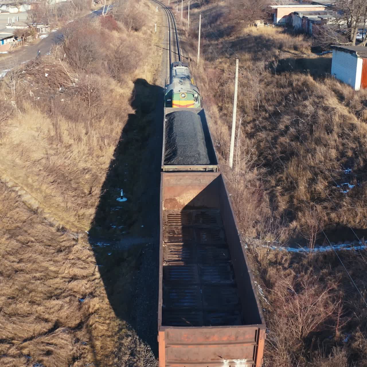 Freight train moving in winter. Top view on a cargo train on rails. Freight transport, railroad and transportation concept. Aerial view.