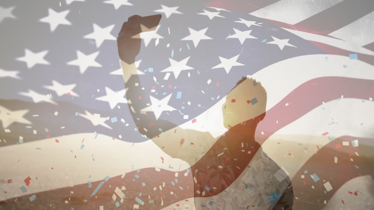 Animation of waving usa flag, confetti falling over african american man taking selfie at the beach