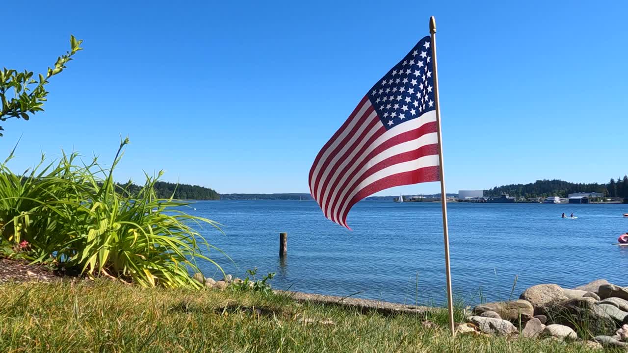 Bandiera americana con stelle e strisce che sventola al vento da un'angolazione bassa in giardino sulla spiaggia dell'Oceano Pacifico, 4 luglio