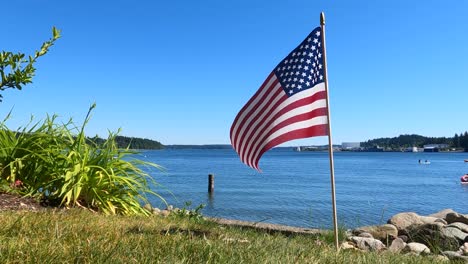 Bandera-Americana-Con-Estrellas-Y-Rayas-Vuela-En-El-Viento-Desde-Un-ángulo-Bajo-En-El-Jardín-En-La-Playa-Del-Océano-Pacífico,-4-De-Julio